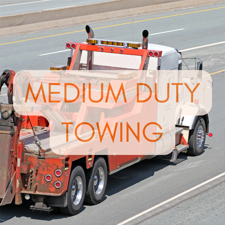 Towing service station in Lake Mills, WI? Topel's Towing & Repair, Inc. A medium-duty tow truck on a highway, equipped to handle larger vehicles and equipment.