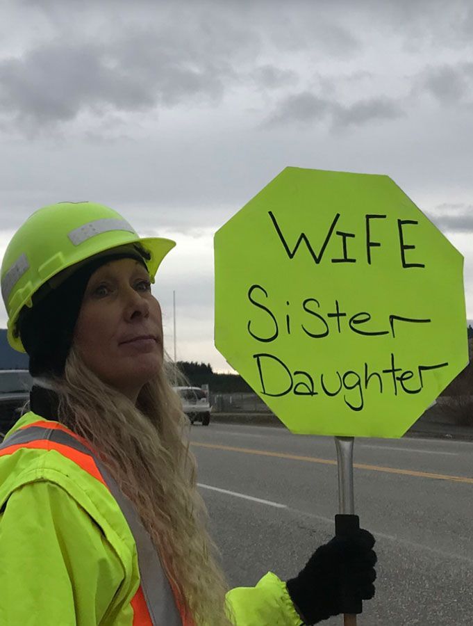 A woman holding a sign that says wife sister daughter