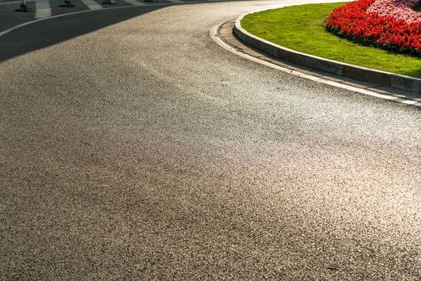 A road with a roundabout and flowers on the side of it.