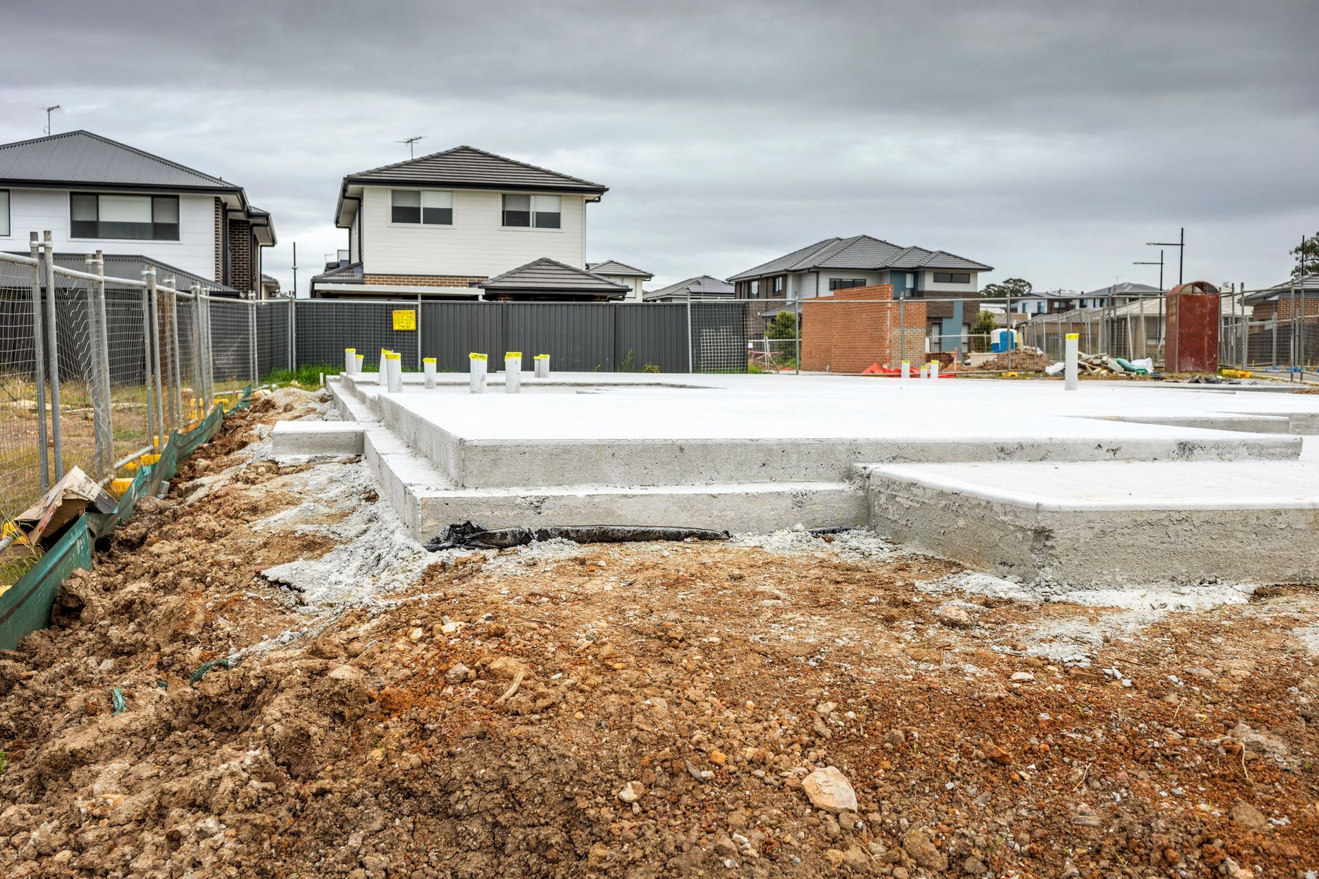 A house is being built in a residential area with a concrete foundation.