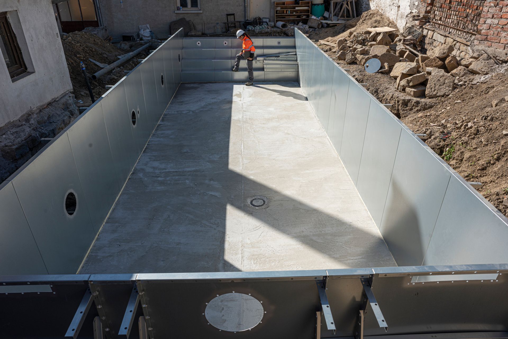 A man is standing in the middle of a swimming pool under construction.