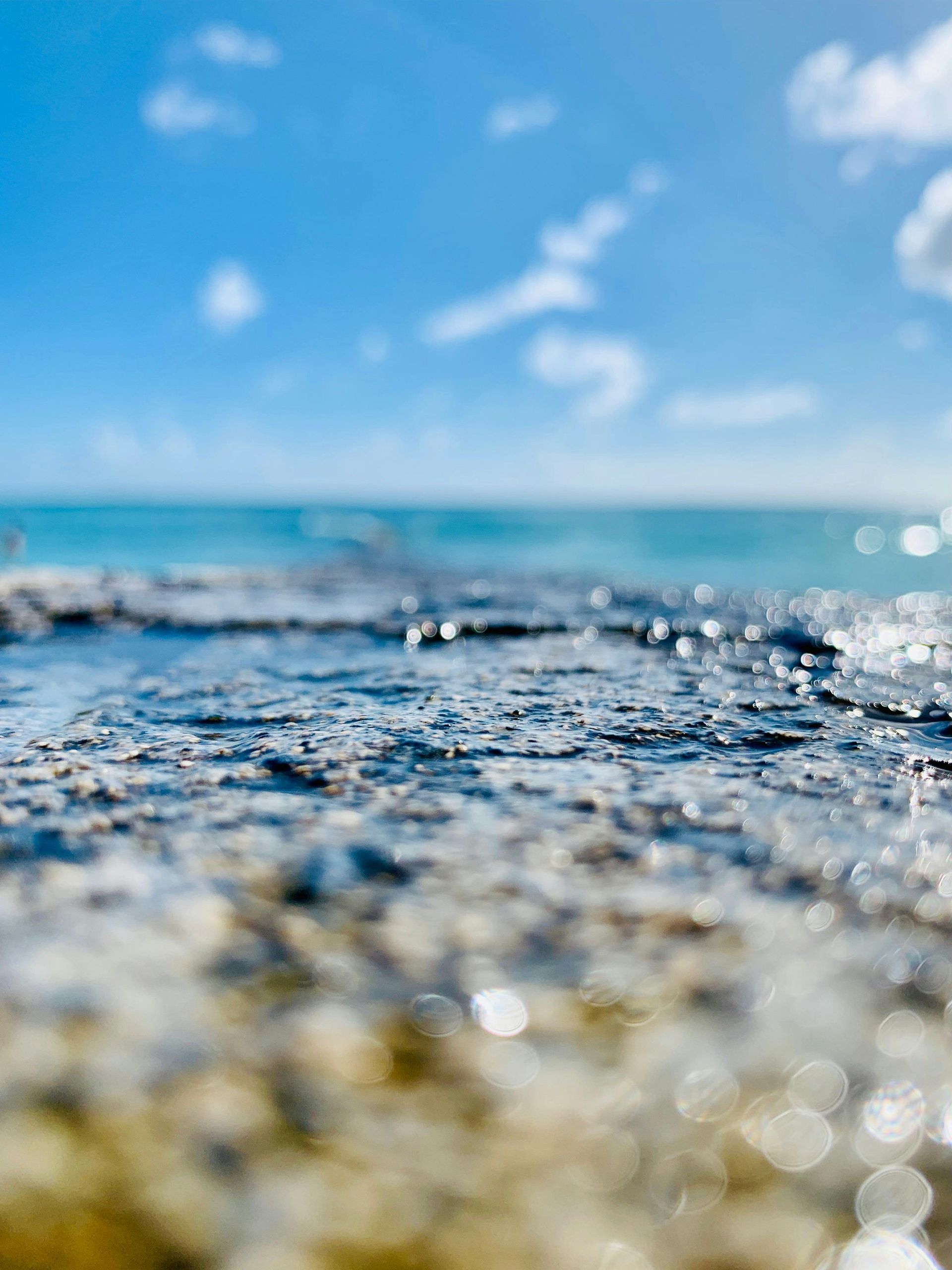 Blurry image taken inches above the water below a blue sky