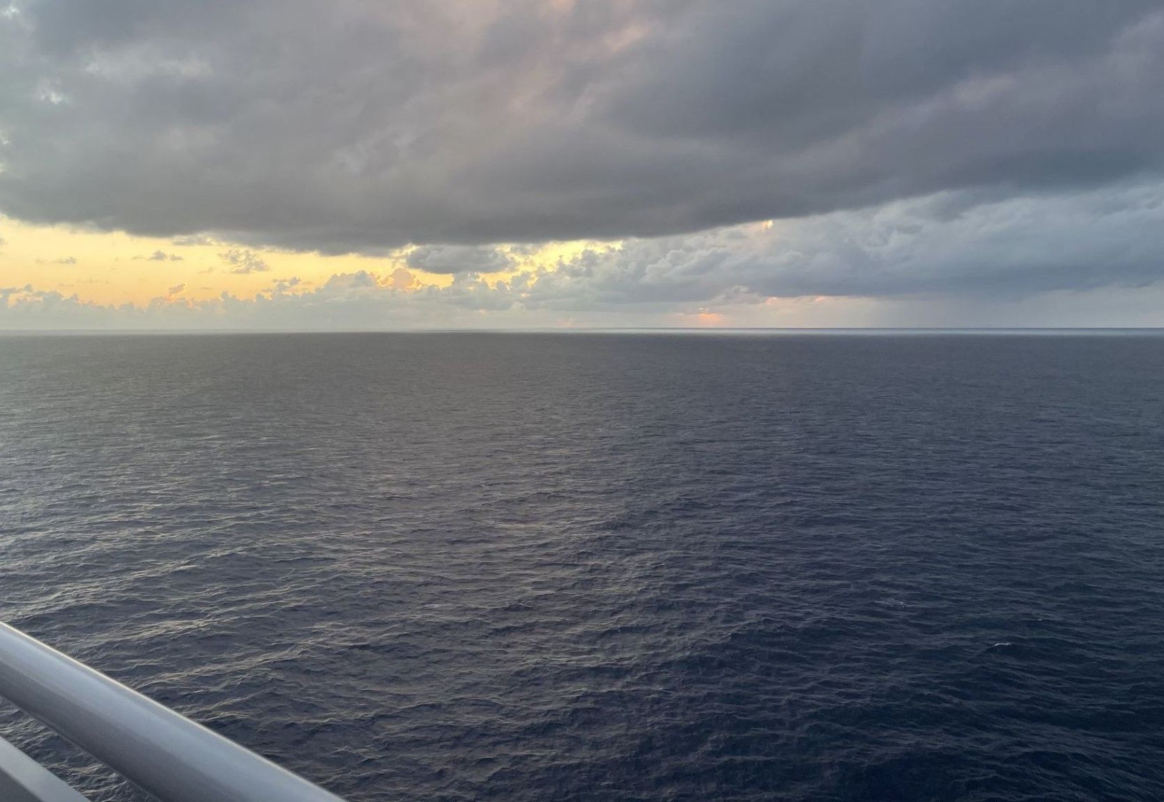 View of calm waters from a cruise ship on an overcast day.