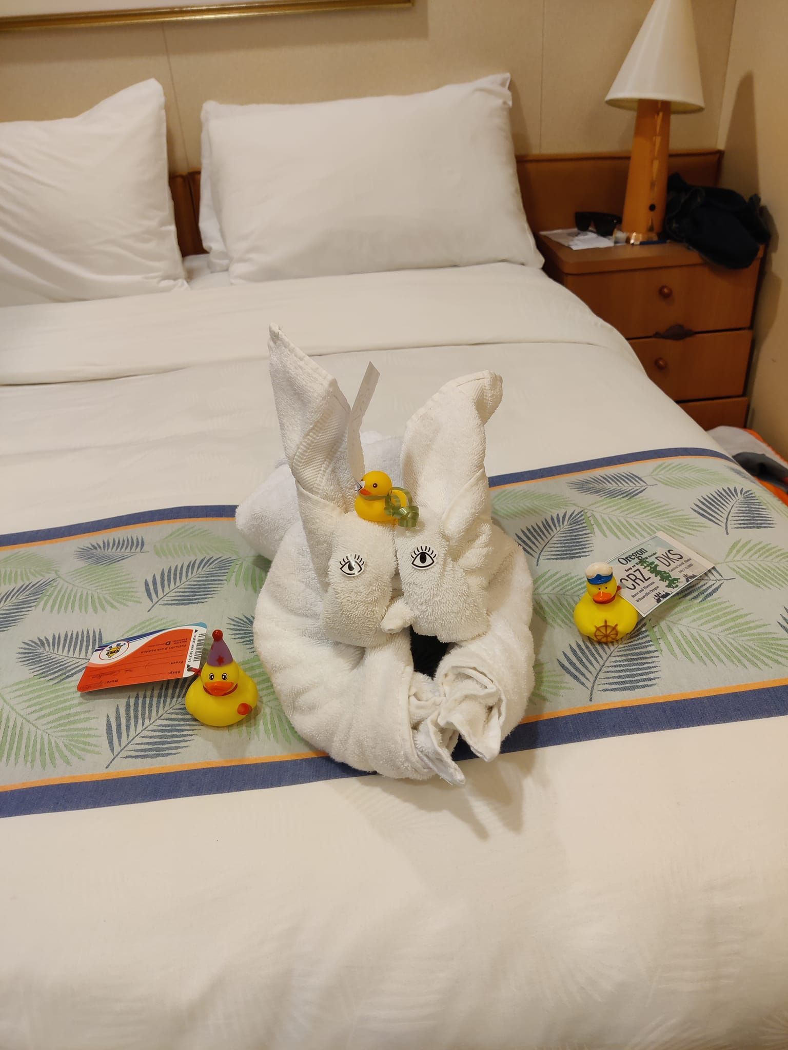 Towel animal and cruise ducks displayed on a cruise bed. 