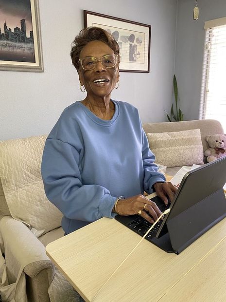 My Haley sitting at her desk in a blue sweatshirt typing on her computer 