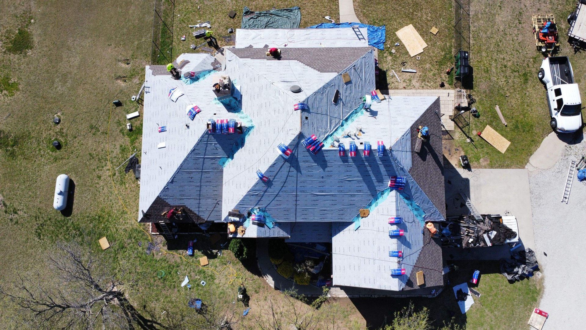 An aerial view of a house under construction with a roof being installed.