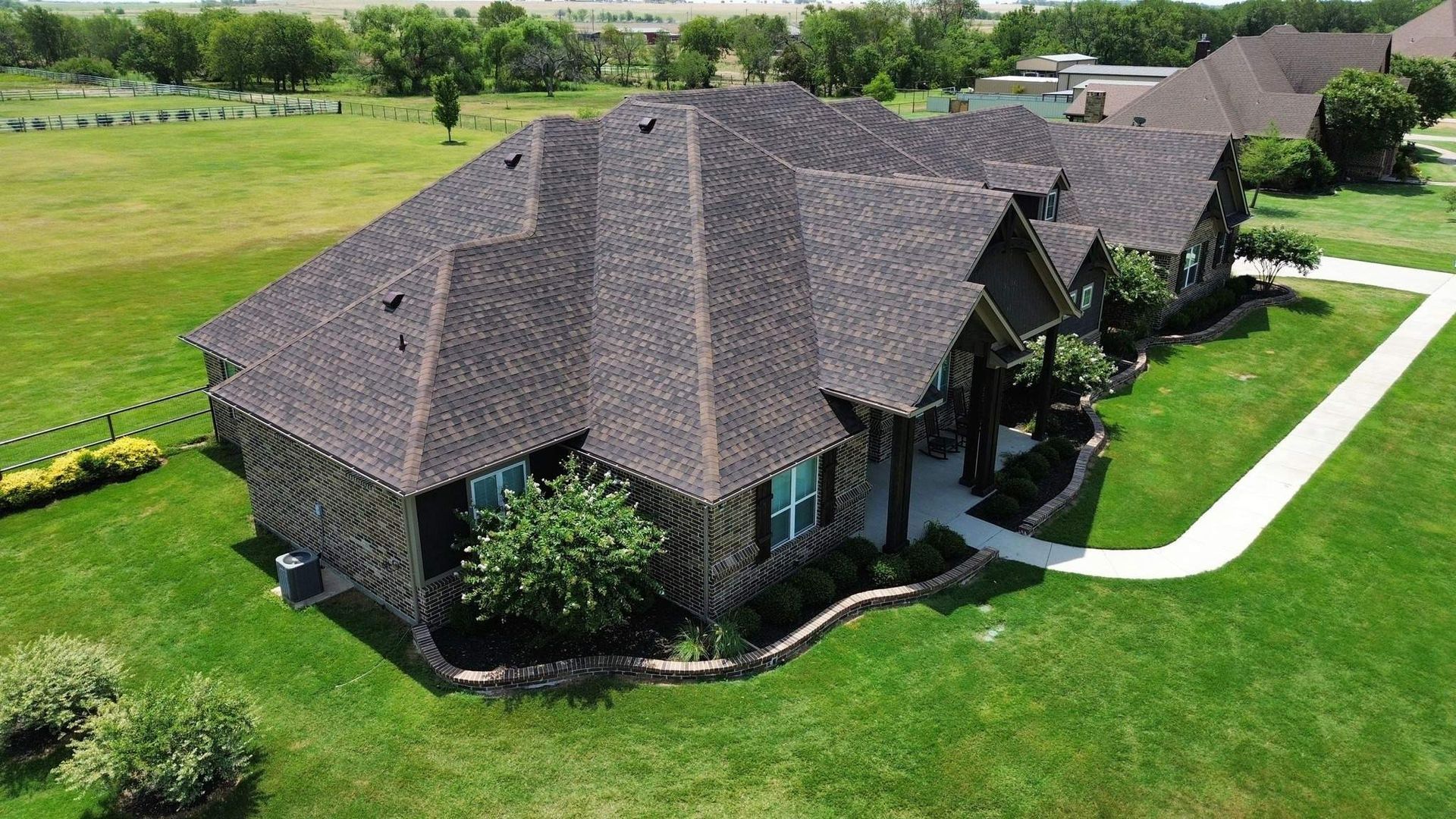 An aerial view of a large house in the middle of a lush green field.