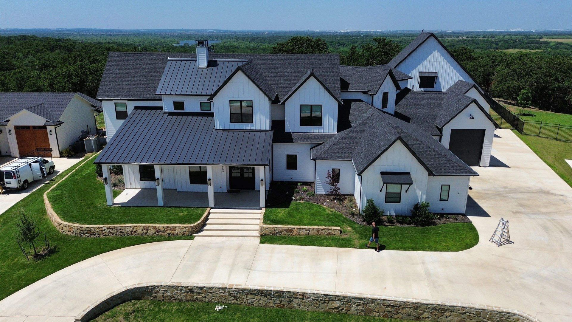 An aerial view of a large white house with a black roof