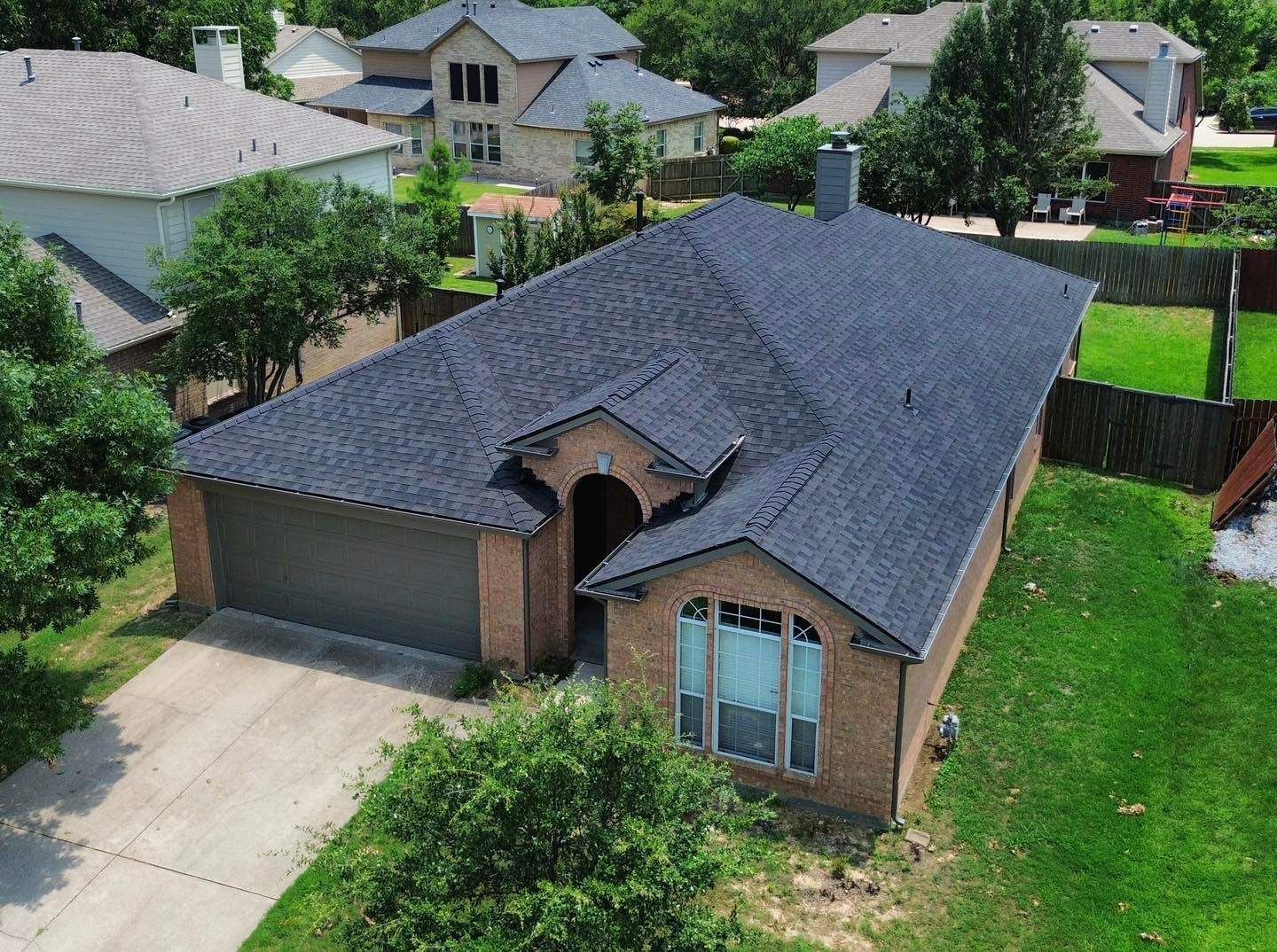 An aerial view of a house with a new roof in a residential area.