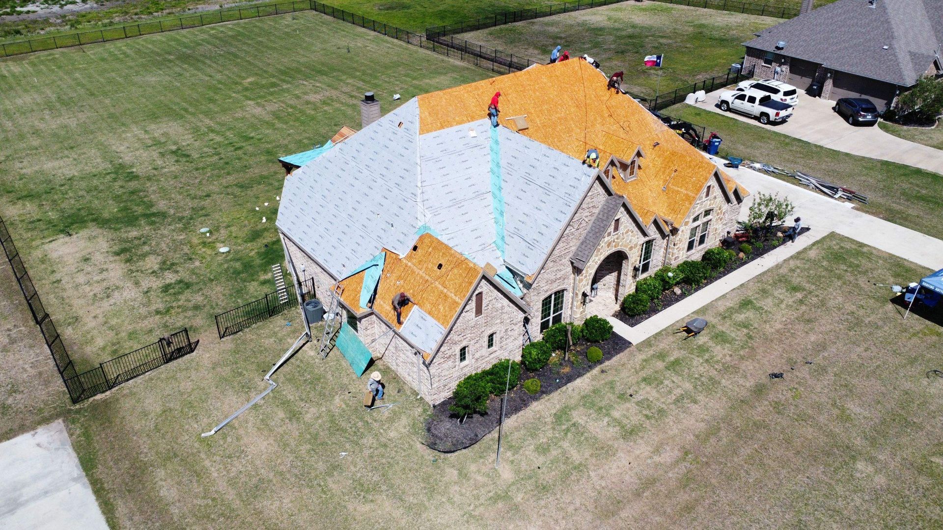 An aerial view of a house under construction with a roof being installed.