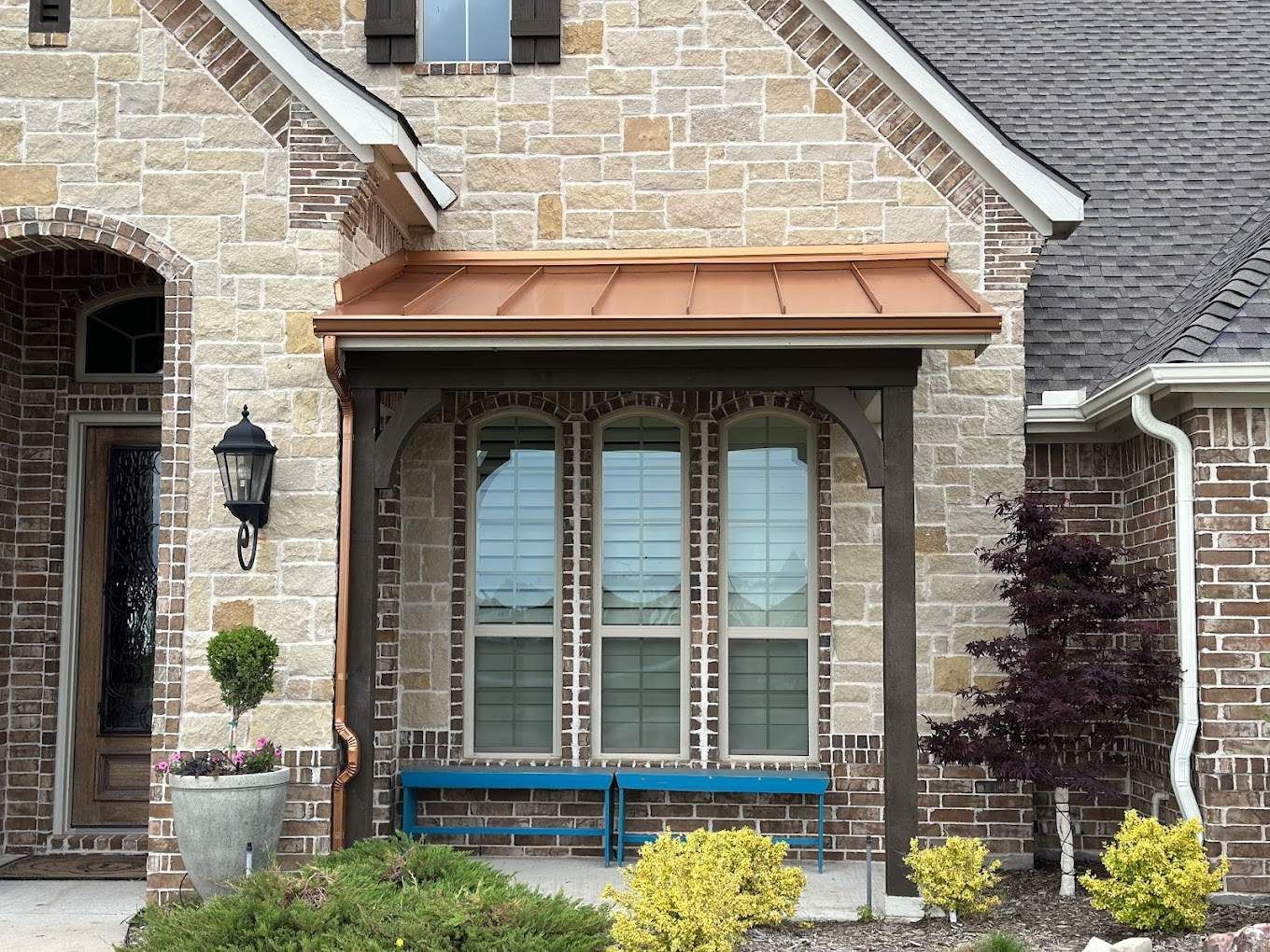 A brick house with a porch and a blue bench