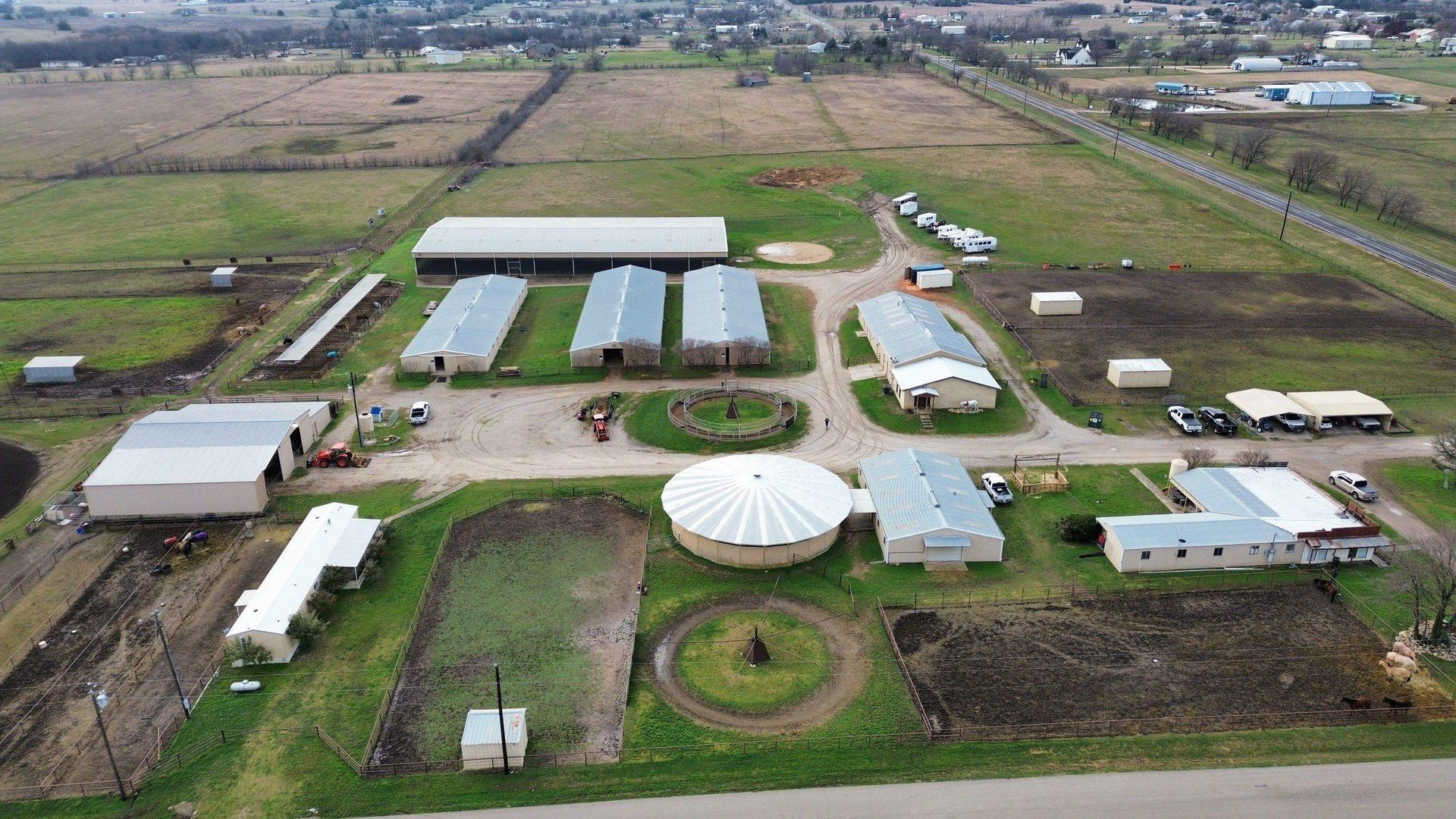 An aerial view of a farm with a lot of buildings and a lot of grass.