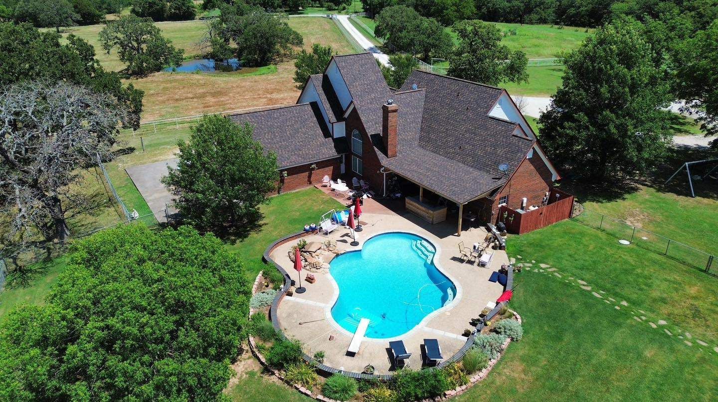 An aerial view of a house with a large swimming pool