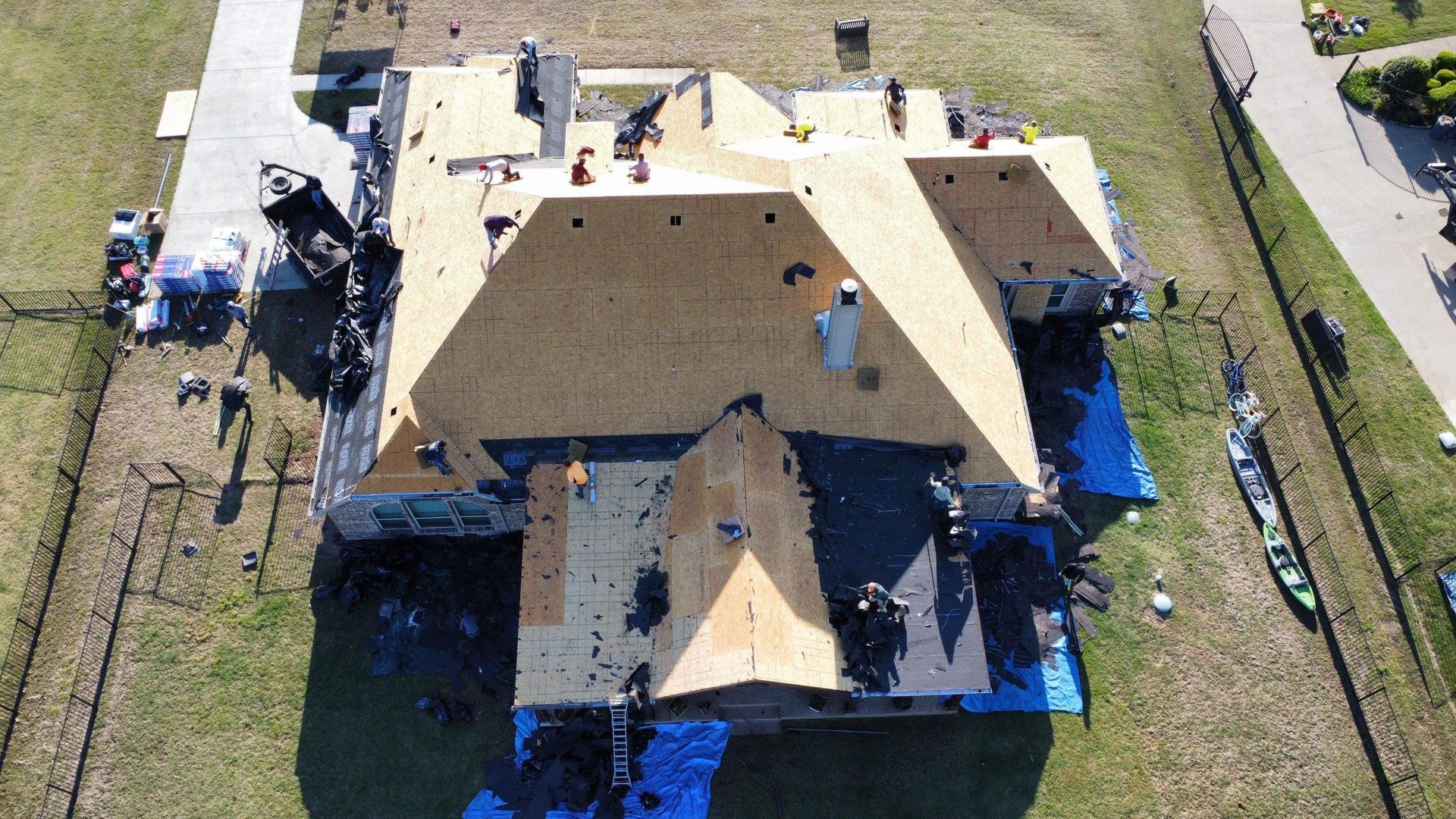 An aerial view of a house under construction with a blue tarp on the ground.