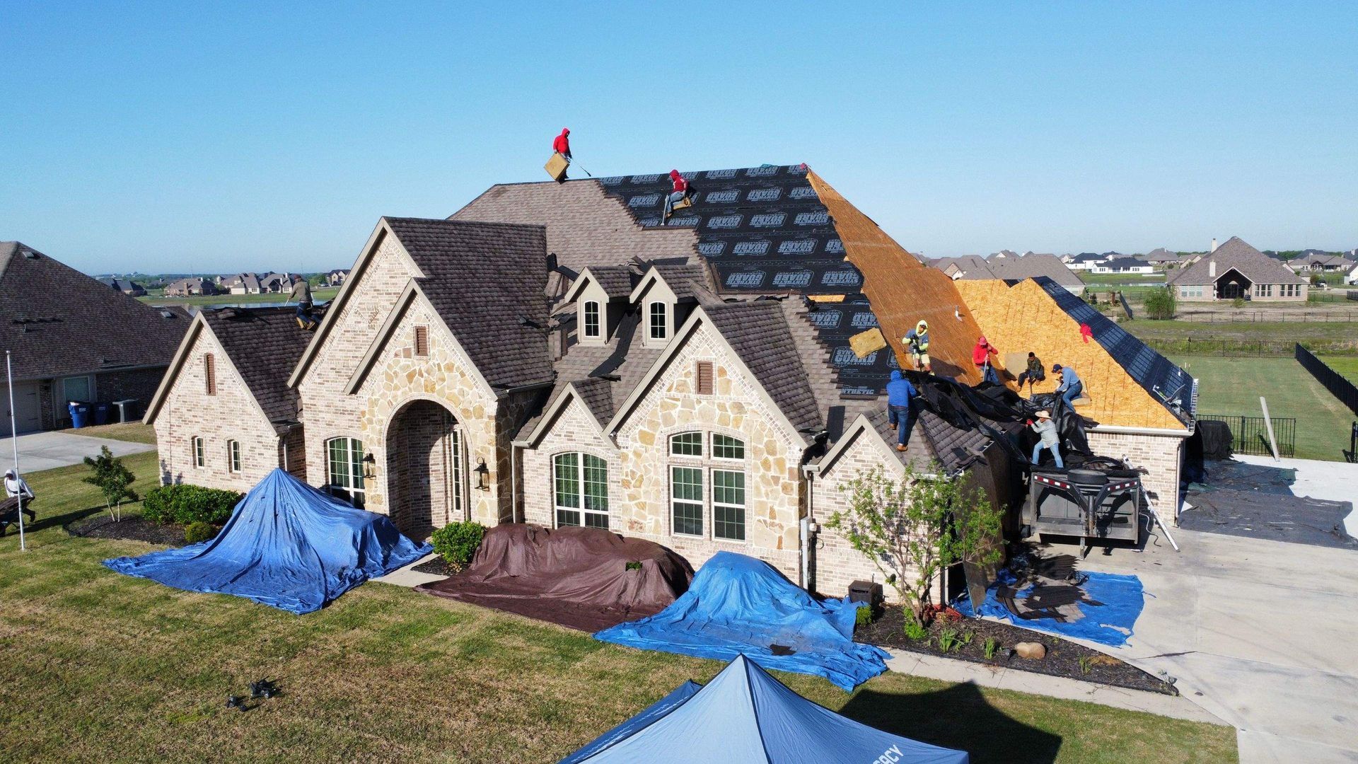An aerial view of a large house under construction with workers on the roof.