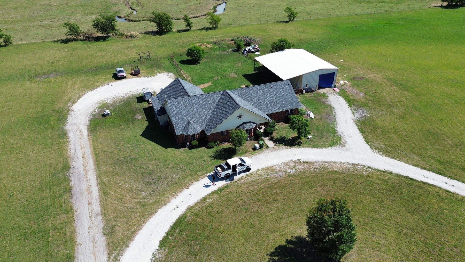 An aerial view of a house in the middle of a grassy field.