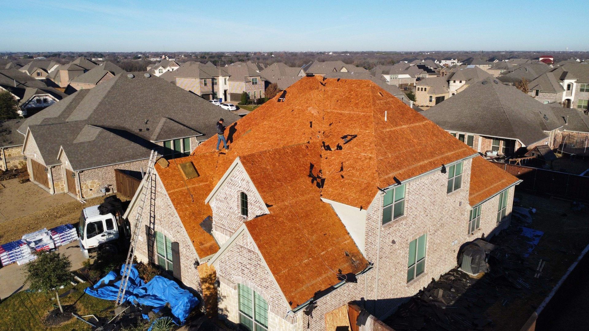 An aerial view of a large house with a red roof in a residential area.