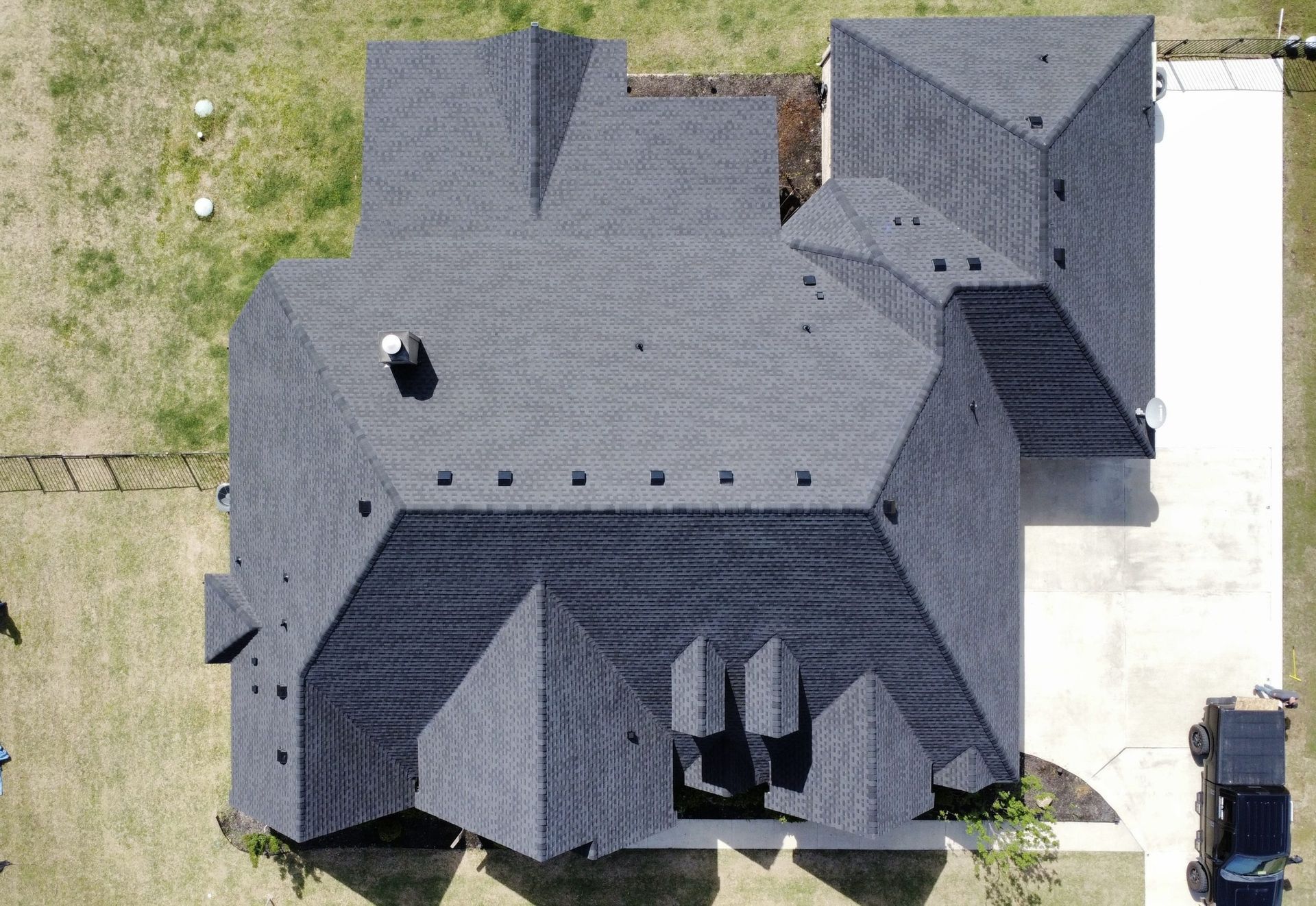 An aerial view of a large house with a black roof.