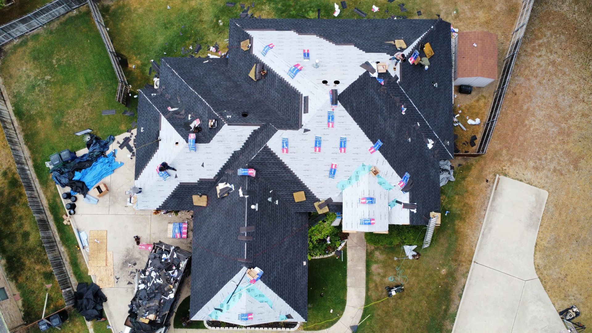 An aerial view of a house under construction with a roof being installed.