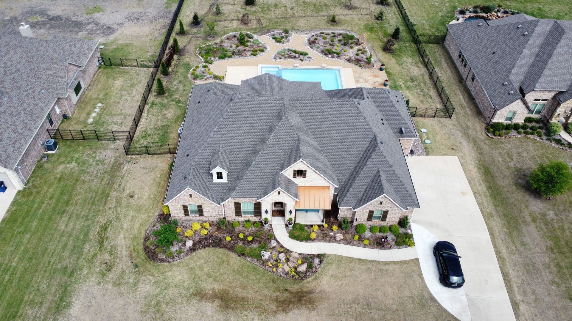 An aerial view of a house with a pool and a car parked in front of it.
