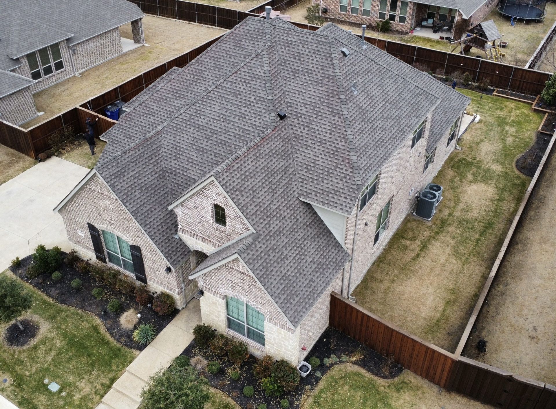 An aerial view of a large brick house with a gray roof.
