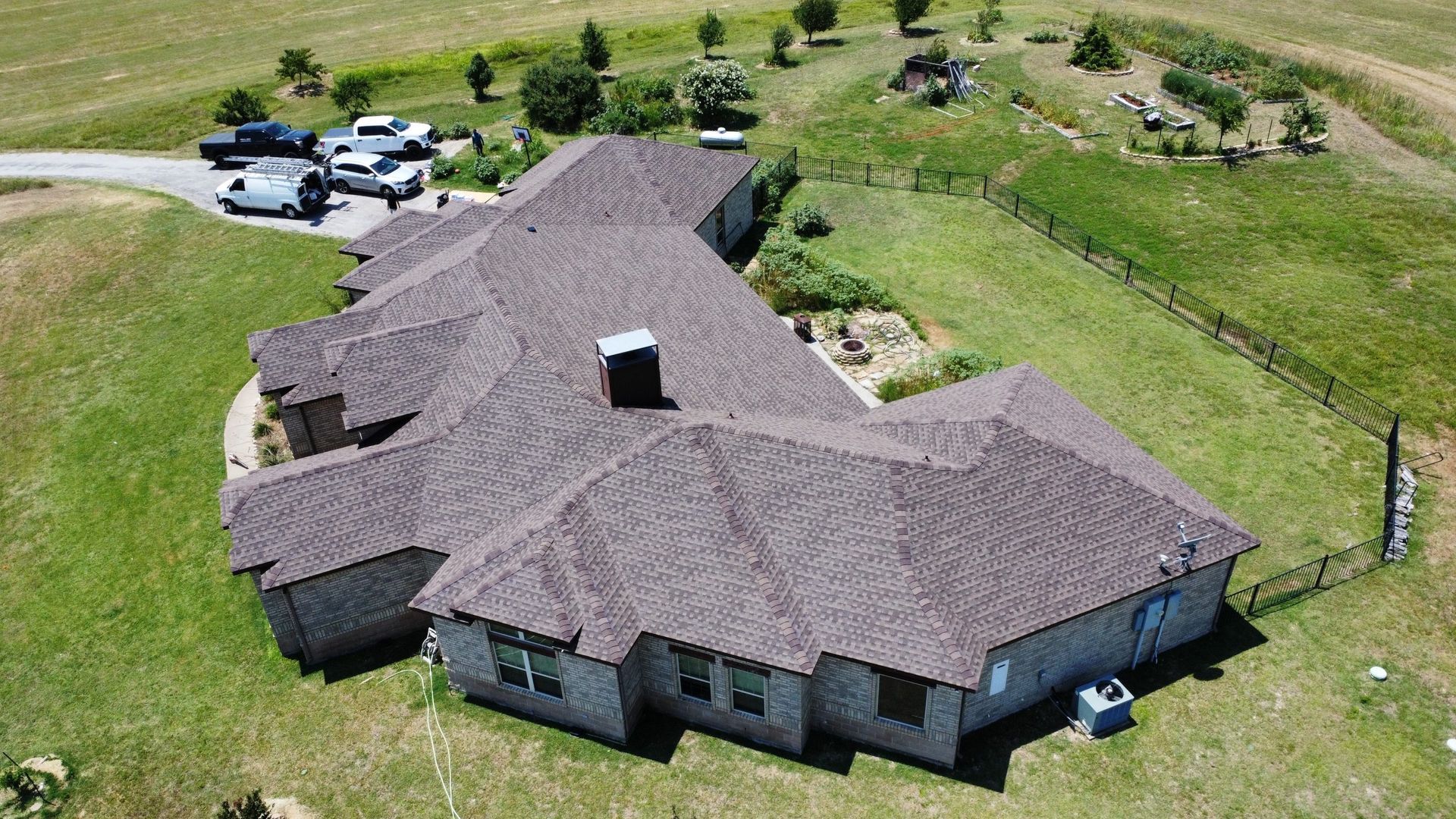 An aerial view of a large house in the middle of a grassy field.