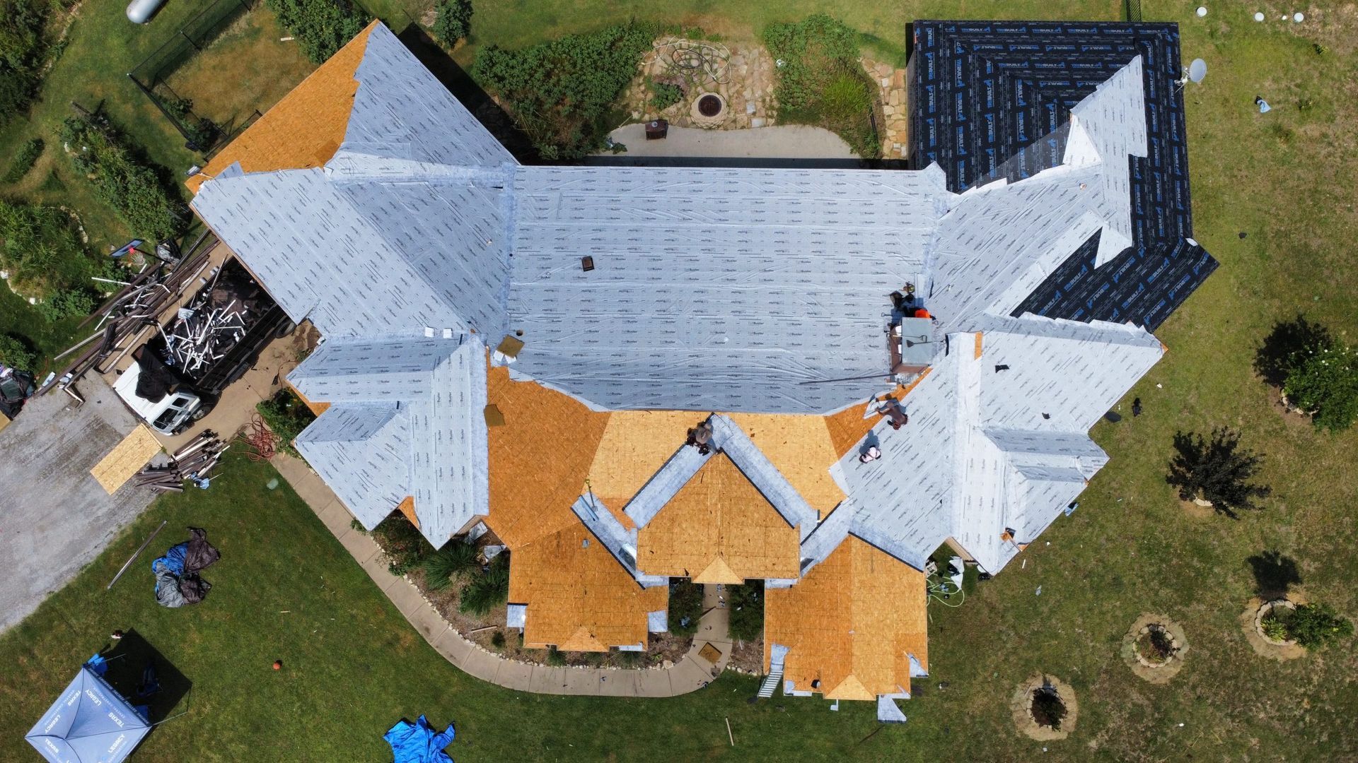 An aerial view of a house under construction with a roof being installed.