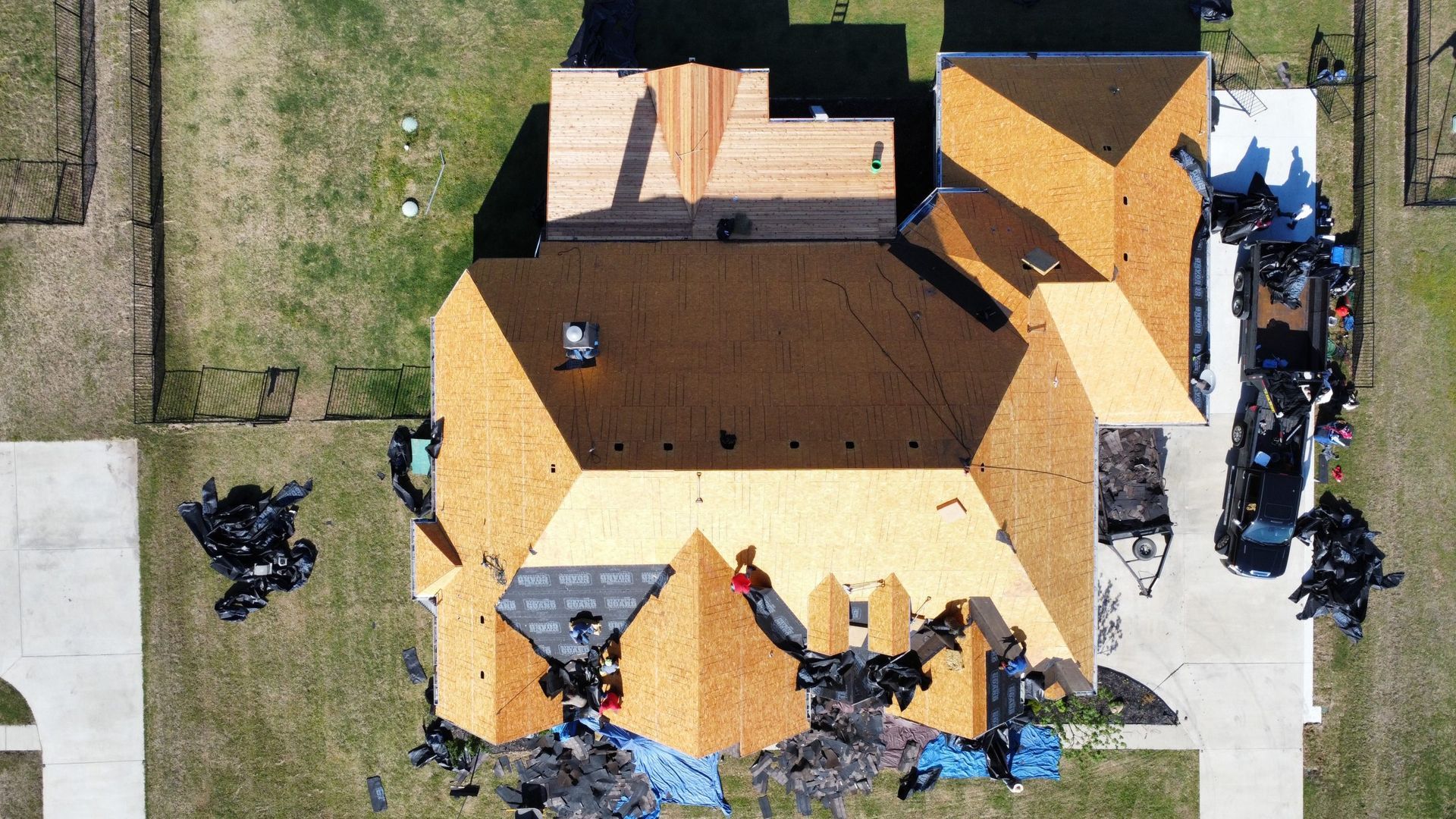 An aerial view of a house under construction with a roof being installed.
