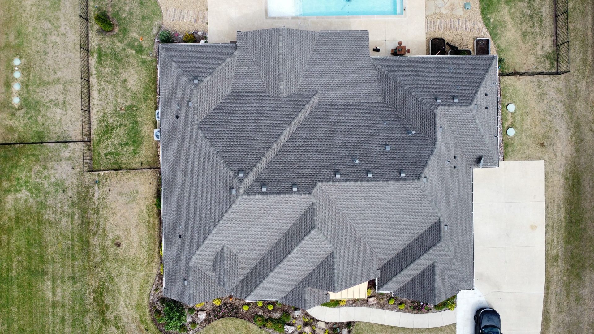 An aerial view of a house with a pool and a car parked in front of it.