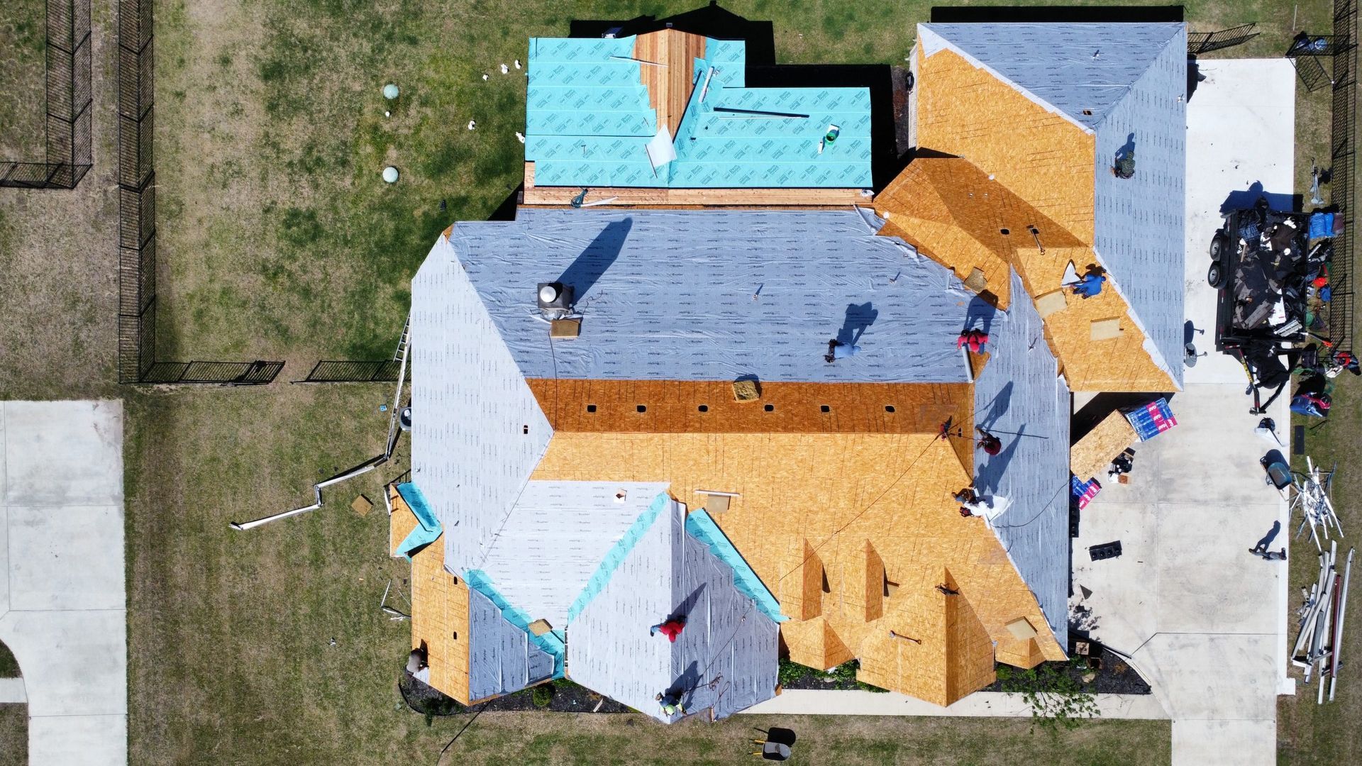 An aerial view of a house under construction with a roof being installed.