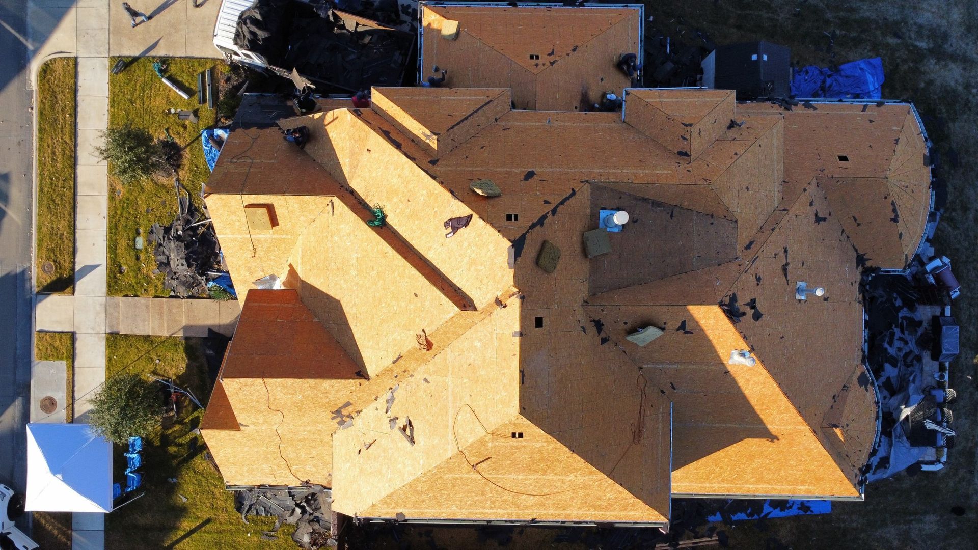 An aerial view of a house under construction with a roof being installed.