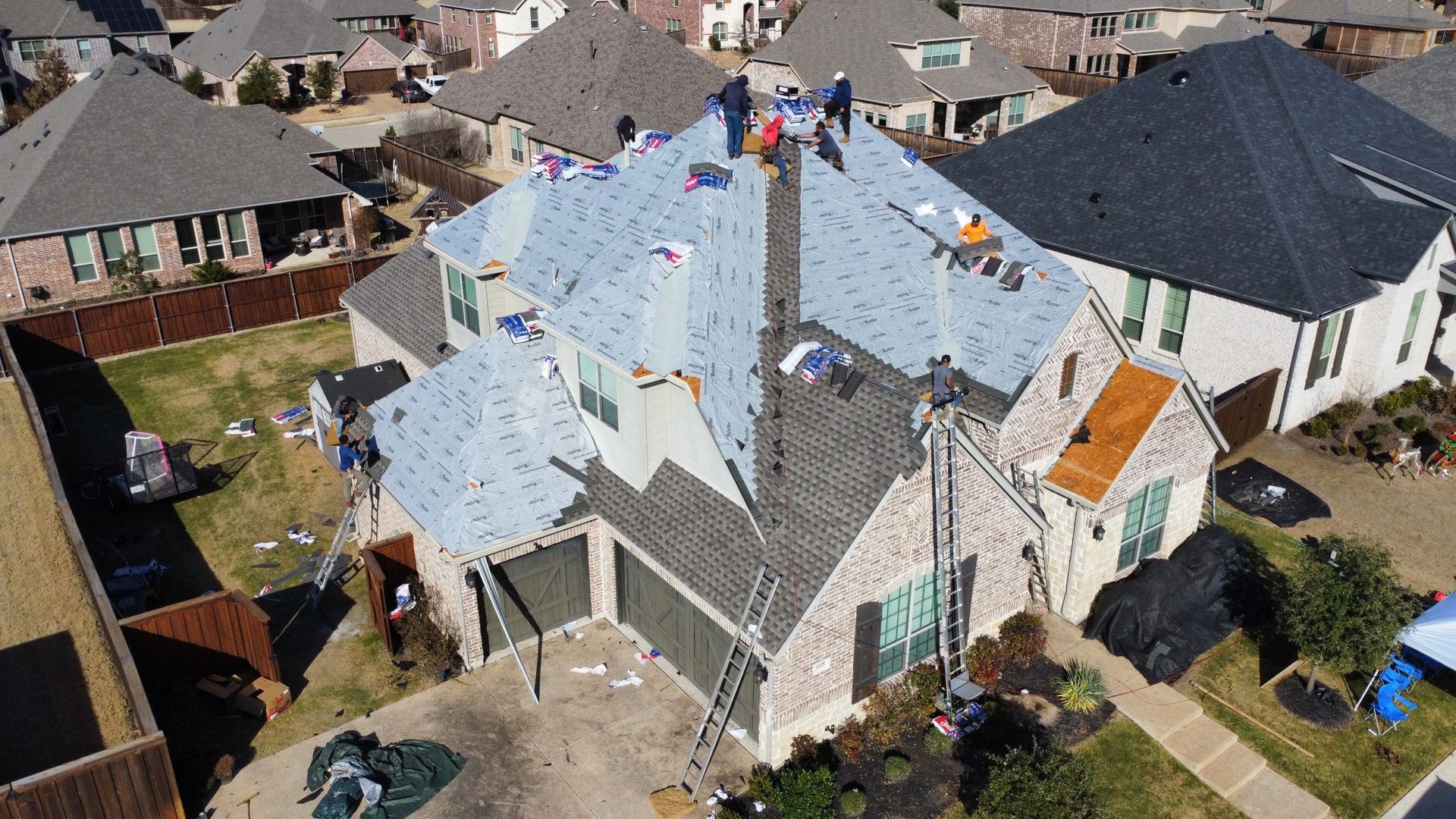 An aerial view of a house being roofed in a residential area.