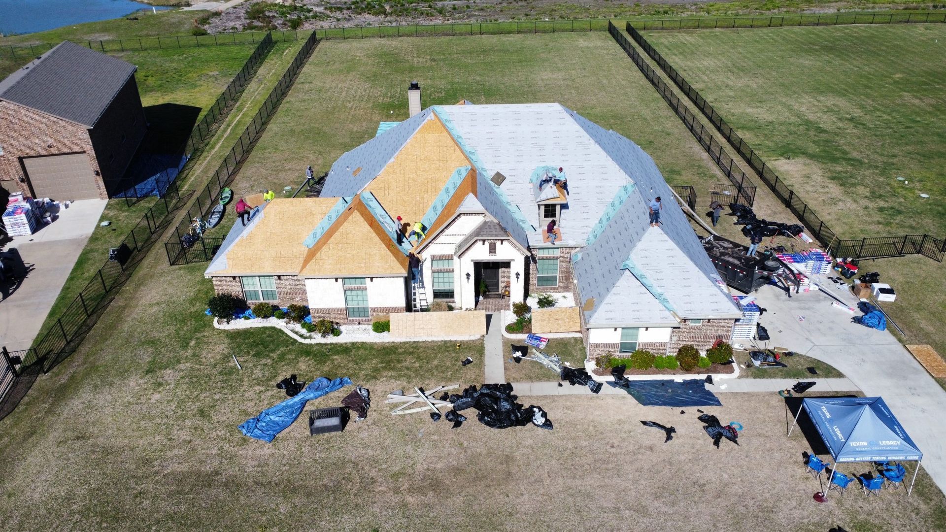 An aerial view of a large house with a roof being installed.
