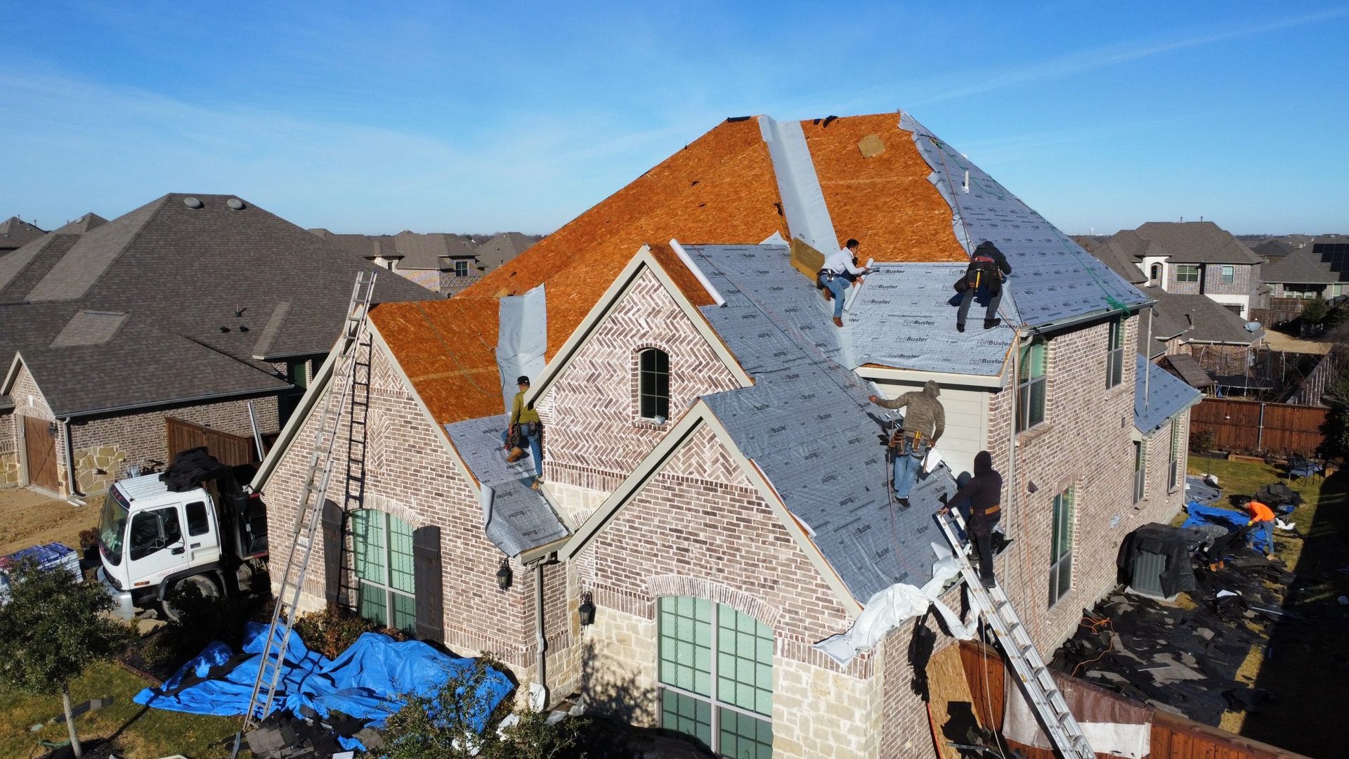 A group of people are working on the roof of a large house.