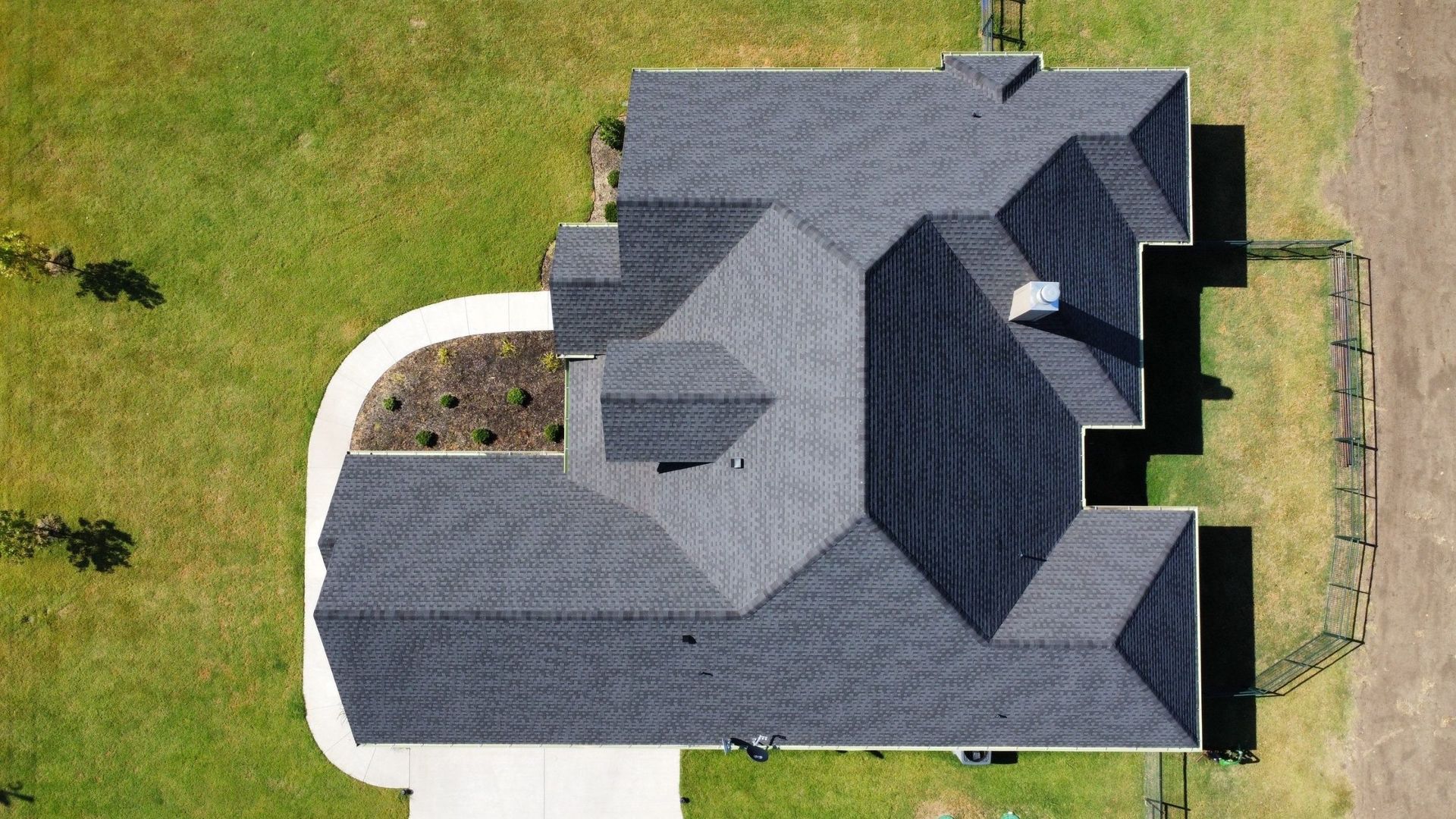 An aerial view of a large house with a gray roof and a driveway.