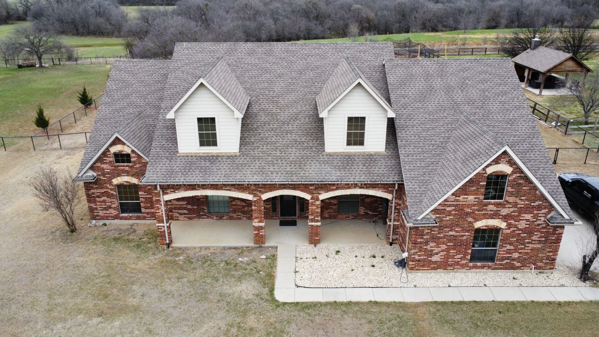 An aerial view of a large brick house with a gray roof.