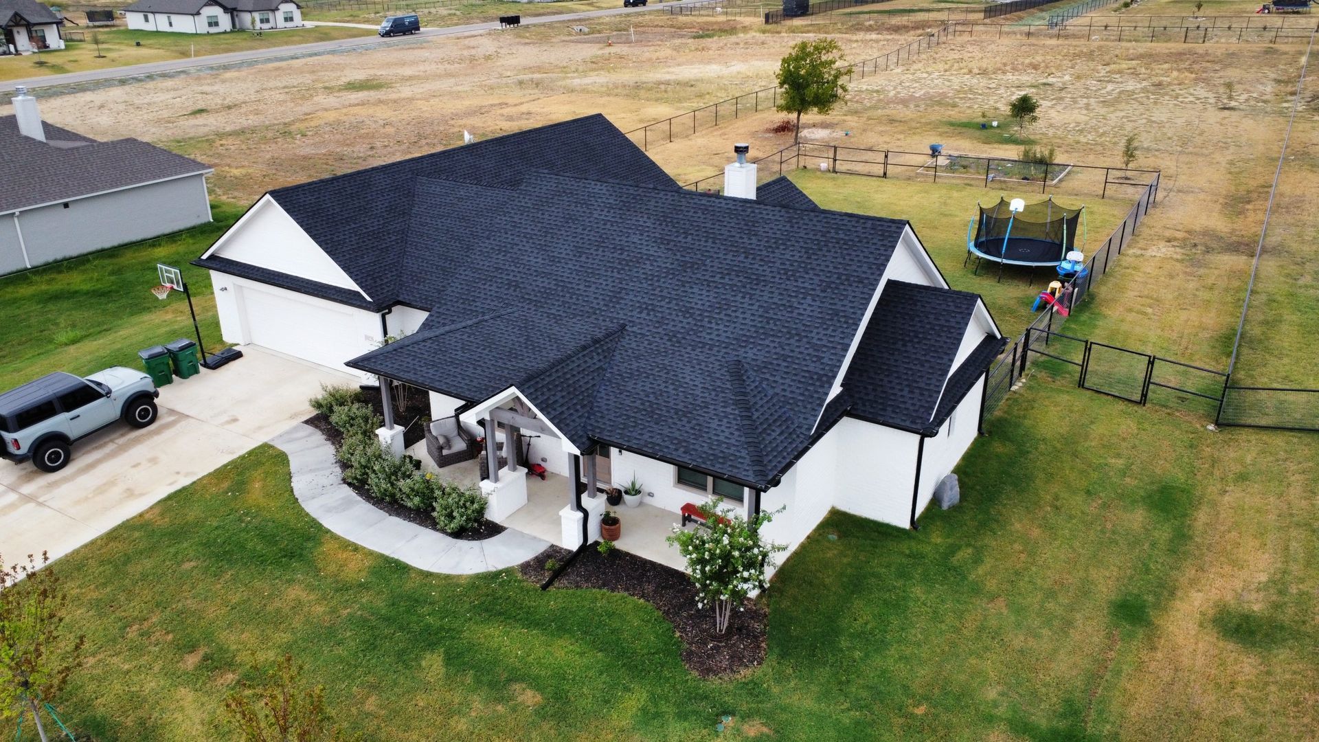 An aerial view of a white house with a black roof.