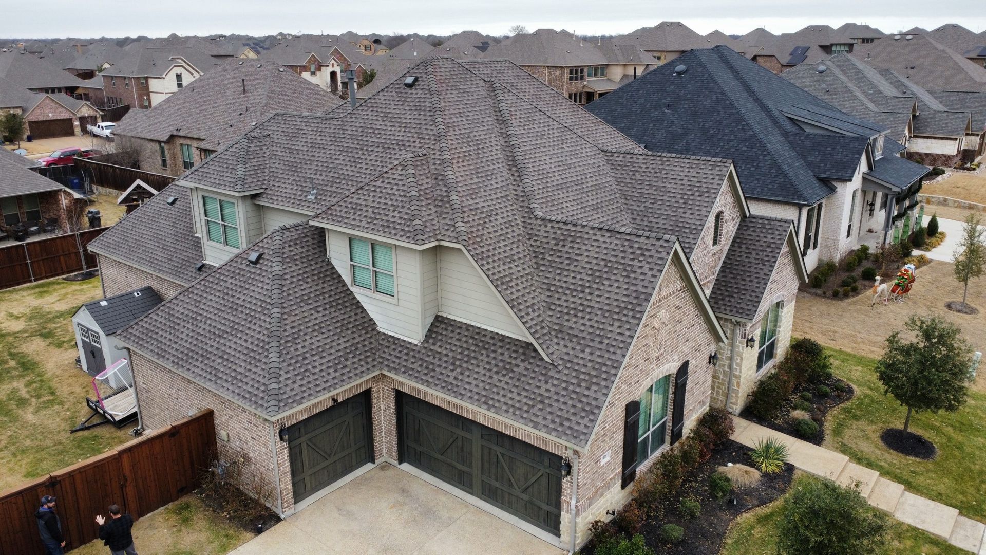 An aerial view of a large brick house in a residential area.