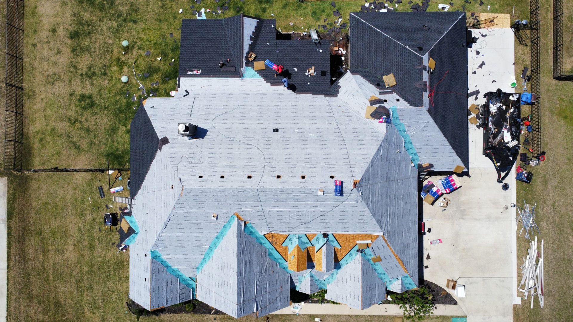 An aerial view of a house under construction with a roof being installed.
