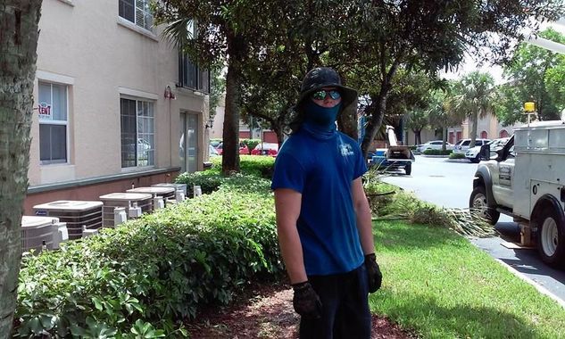 A man wearing a mask and a hat is standing in front of a building.