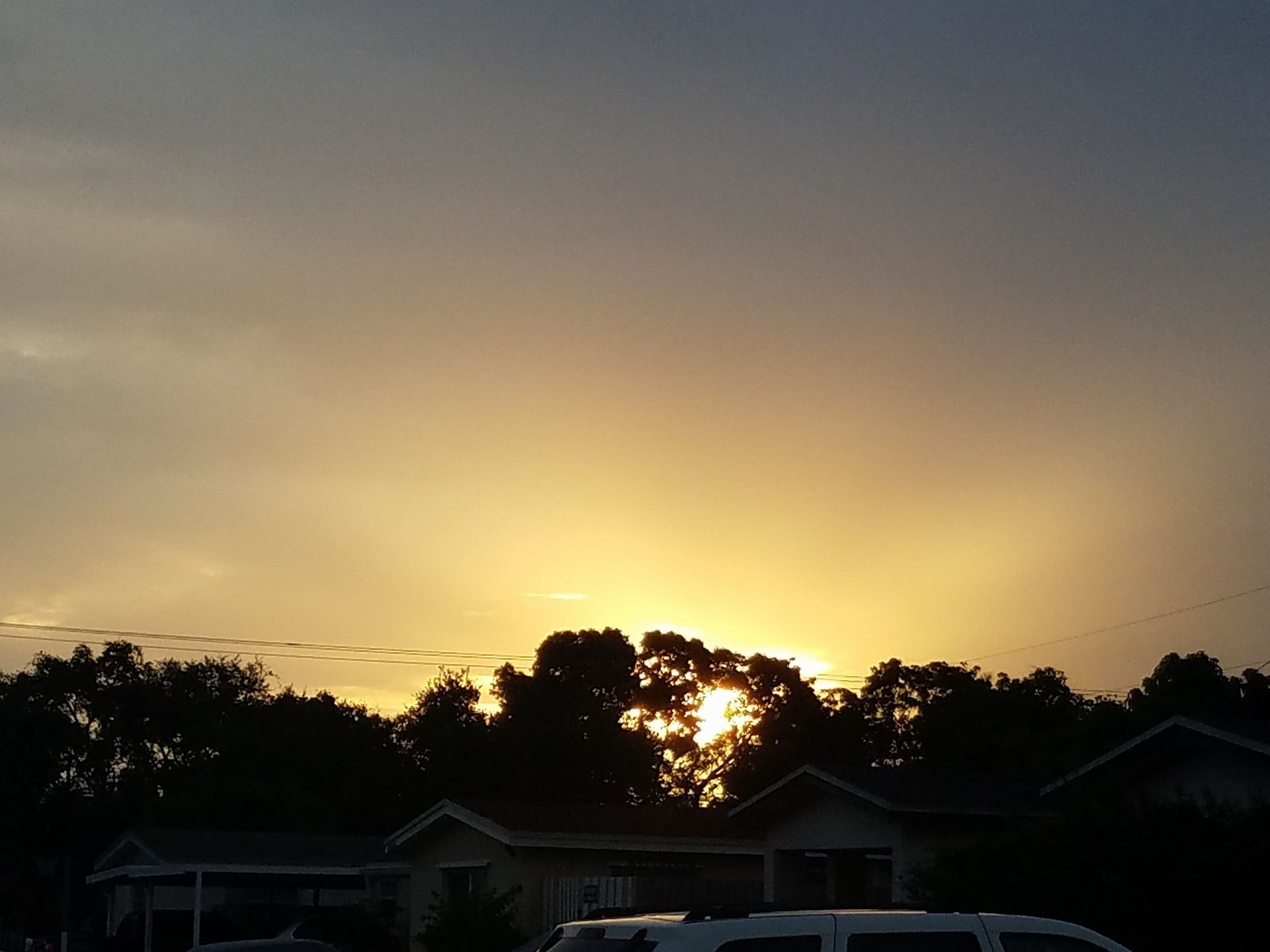 The sun is setting behind a row of houses