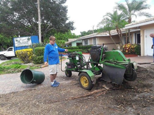 A man is standing next to a john deere stump grinder.