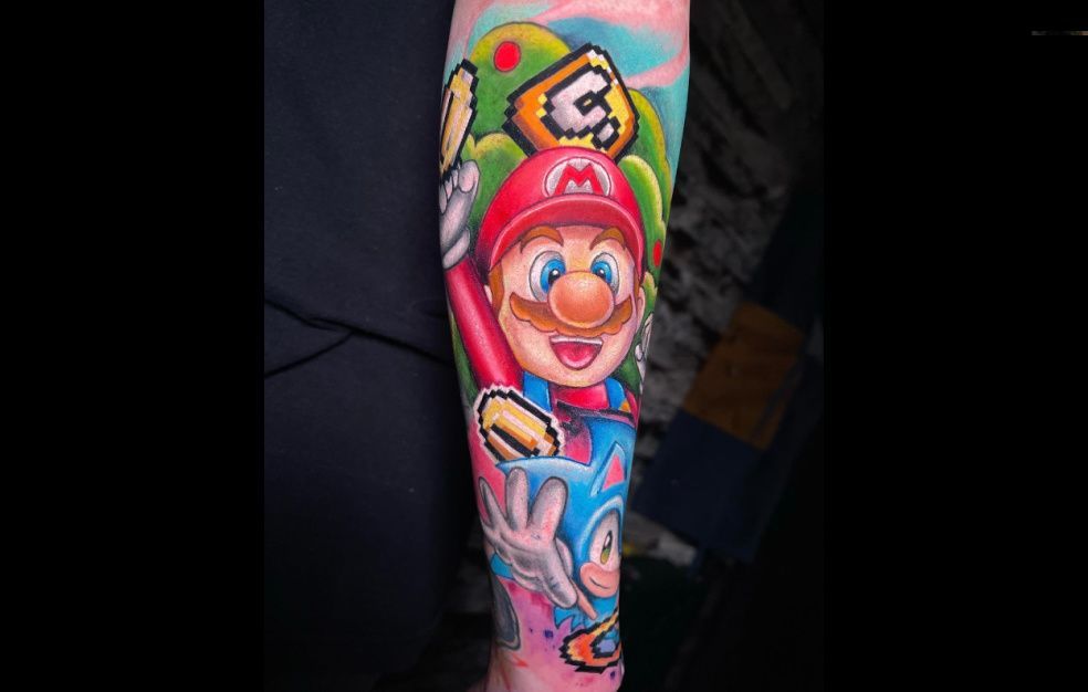 a person has a tattoo of mario and sonic on their arm .