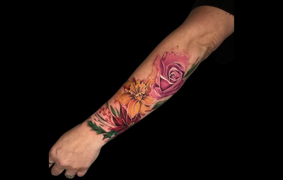 a woman has a tattoo of flowers on her forearm .