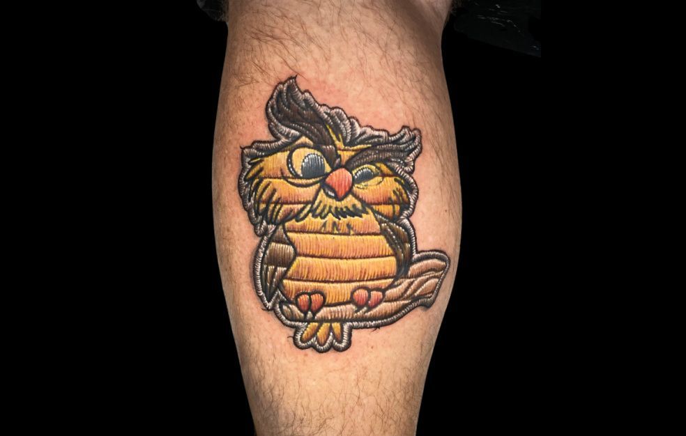 a person has a tattoo of an owl on their leg .