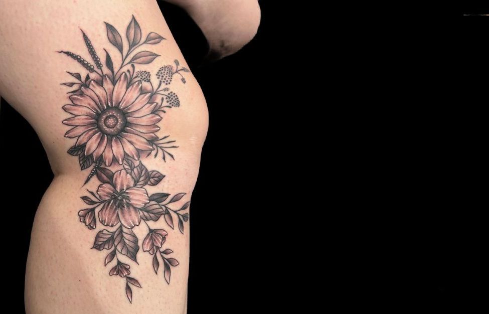 a woman has a tattoo of flowers on her knee .