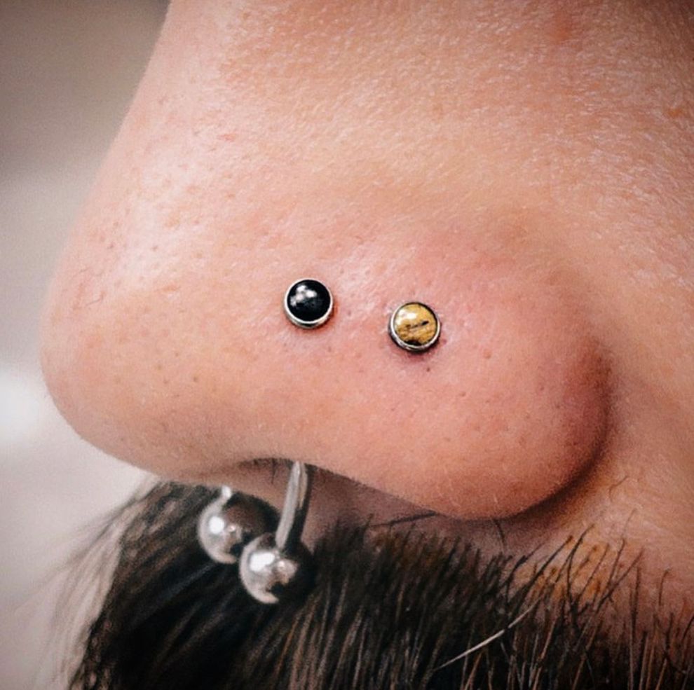 a close up of a person 's nose with two piercings .