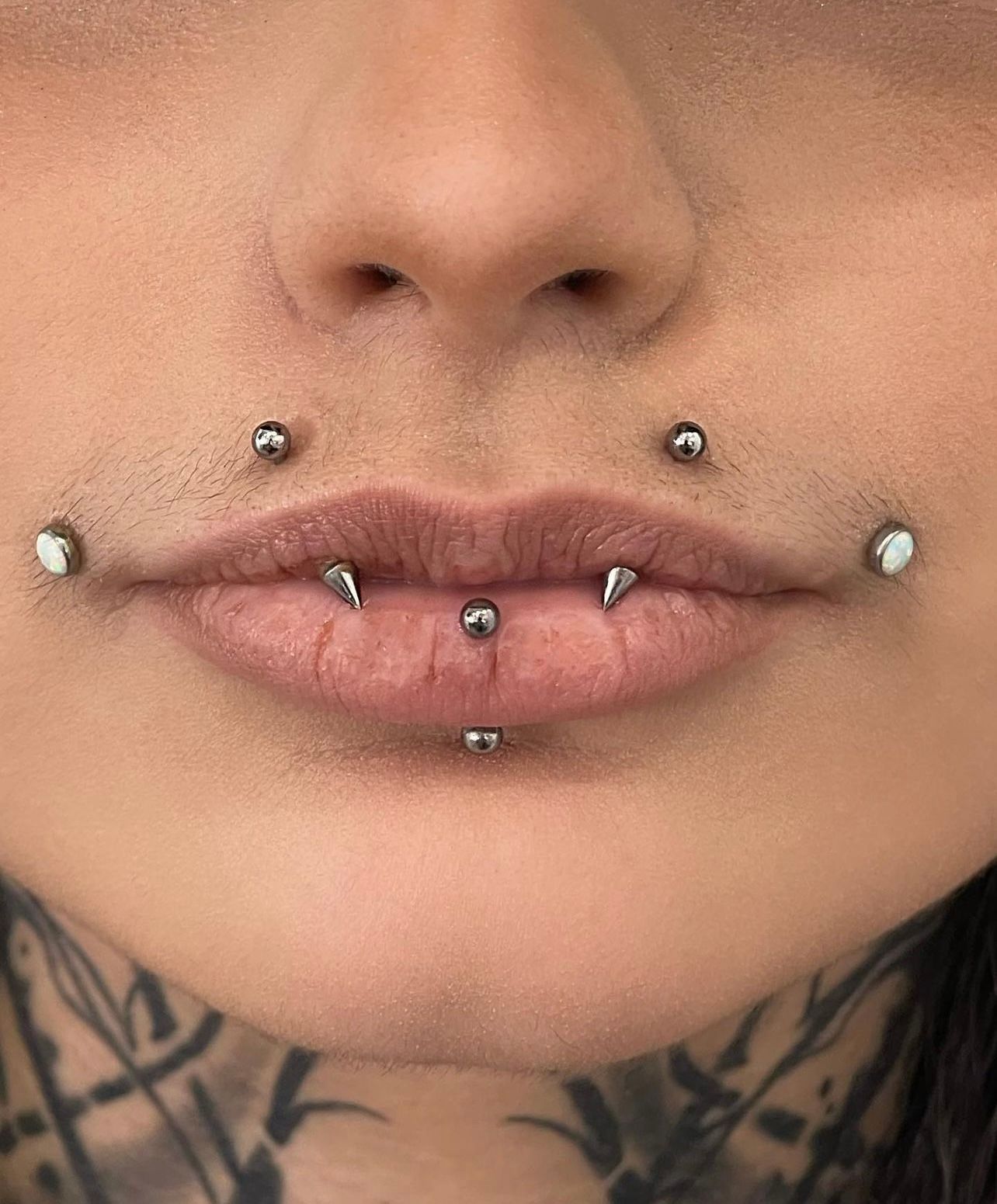 a close up of a woman 's lips with multiple piercings .