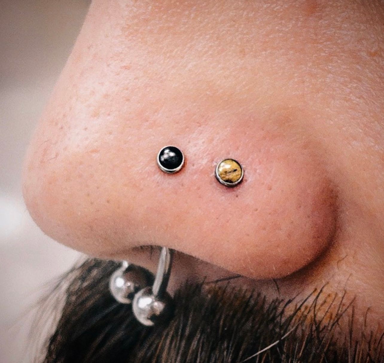 a close up of a person 's nose with two piercings .