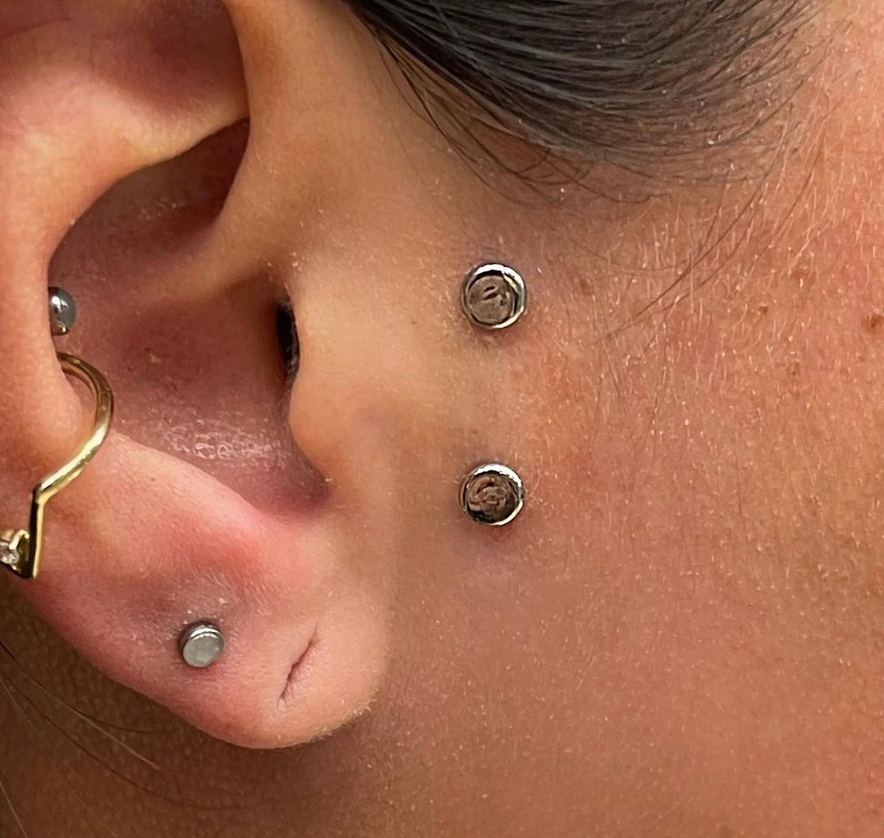 a close up of a woman 's ear with multiple piercings .